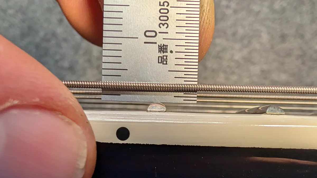 Luthier David Aitken measuring string action height at 2.0mm at the 12th fret on the Douglas workbench